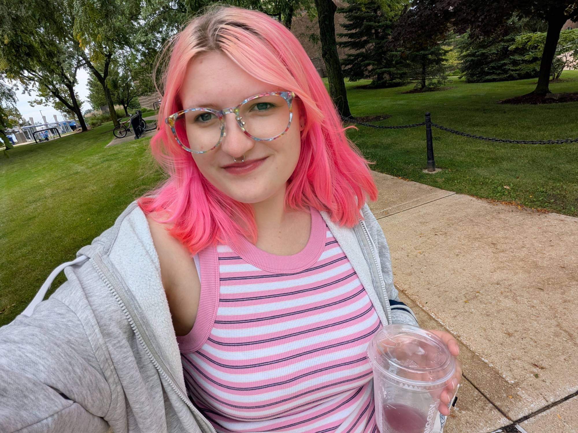 person with pink hair smiling at the camera